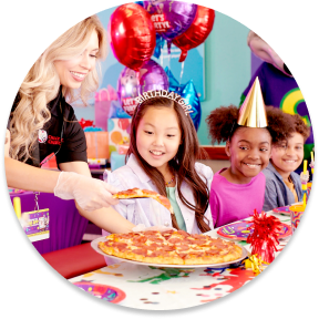 Niños con sombreros de cumpleaños mientras les sirven pizza