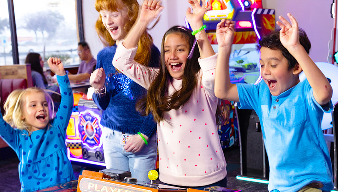 niños celebrando una gran victoria en un juego arcade