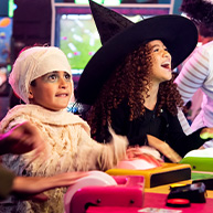 Dos niños disfrazados de Halloween jugando a un juego. Un niño vestido de momia de Halloween y el otro con un sombrero de bruja de Halloween.
