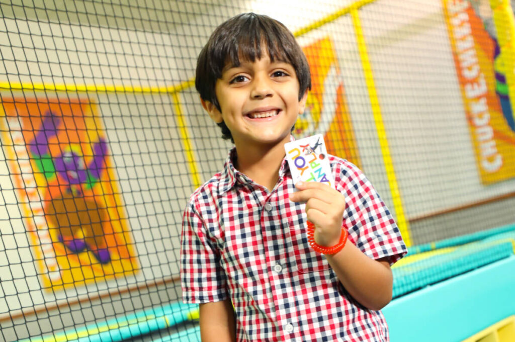 Un niño con una tarjeta Juega todo lo que puedas en la zona de trampolines
