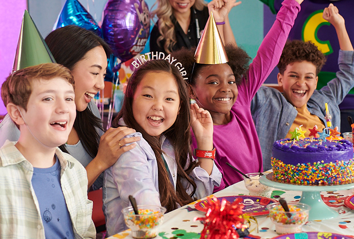 una niña festejando su cumpleaños con un pastel morado y sus amigos